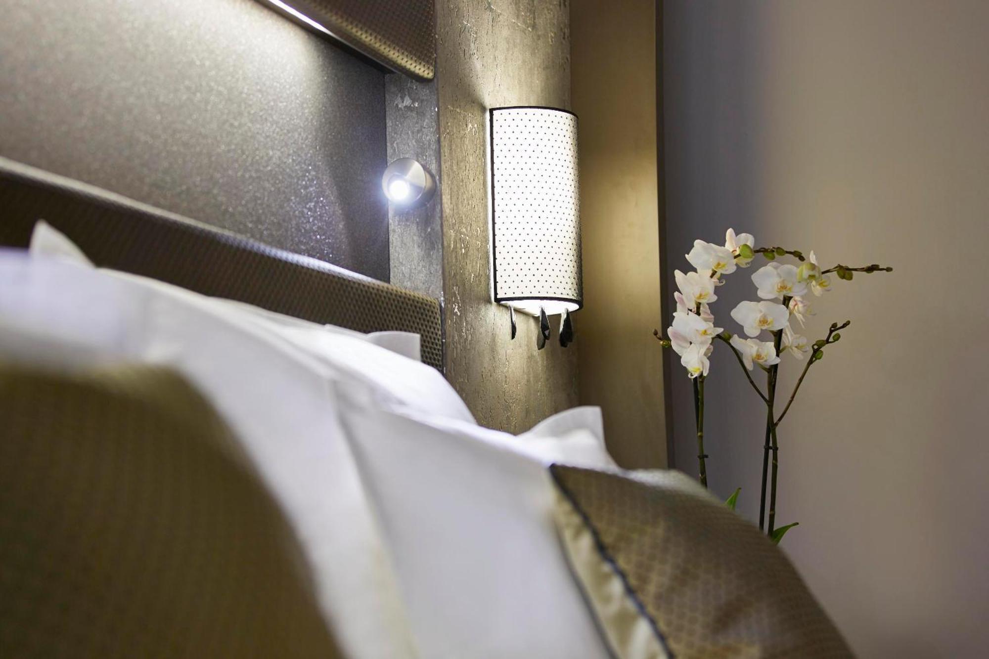 فندق ستيجنبرجر آم كانزليرمت برلين الغرفة الصورة The photo displays a cozy bedroom scene. In the foreground, there are neatly arranged white pillows on a bed, suggesting comfort. A stylish wall sconce is mounted on the headboard, providing soft lighting. To the side of the bed, there is a decorativ